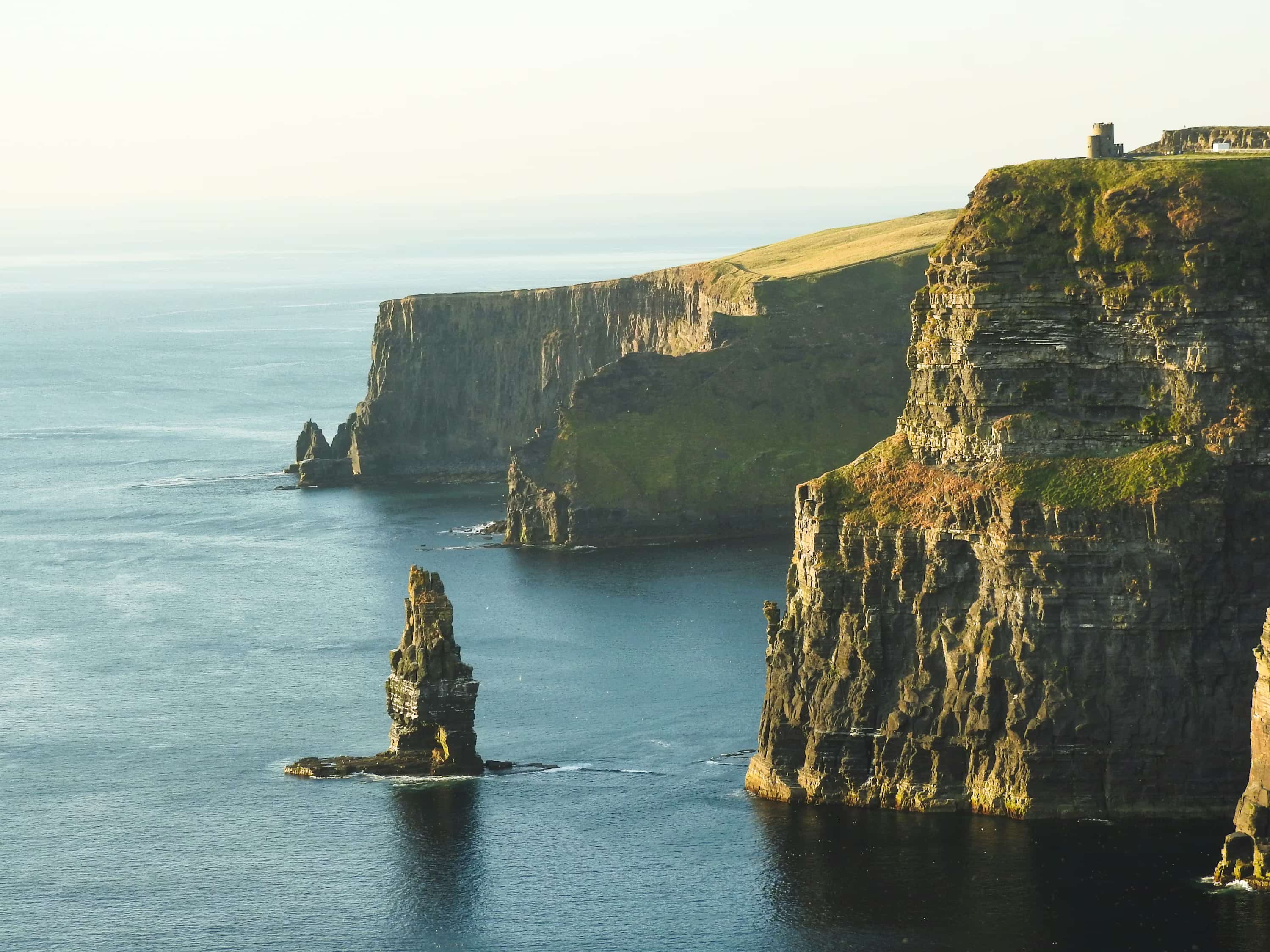 rock formation beside sea under white sky