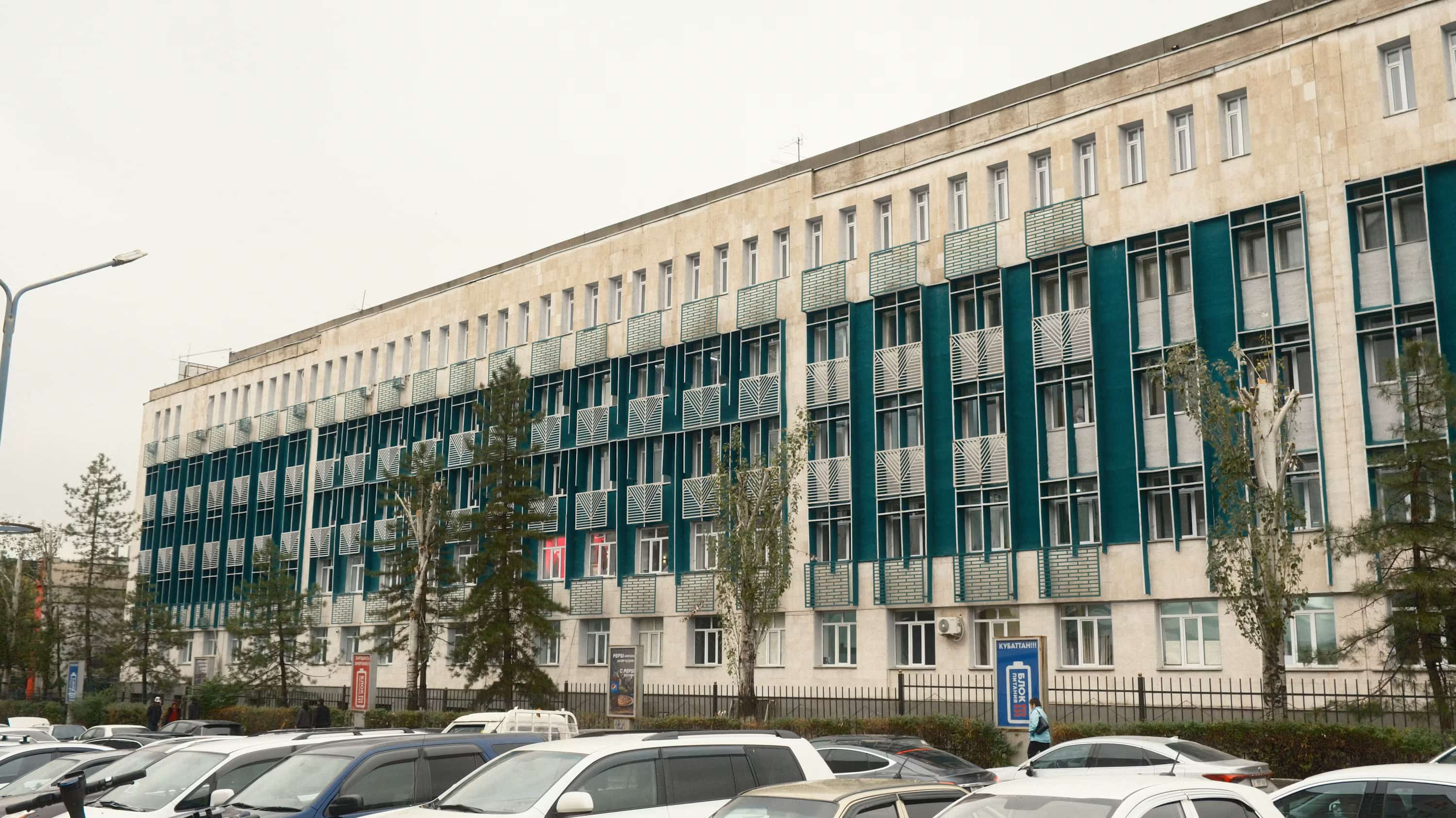 A row of parked cars in front of a large building