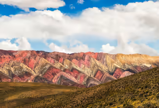 brown and gray mountains under white clouds and blue sky during daytime