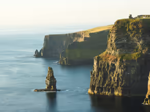 rock formation beside sea under white sky